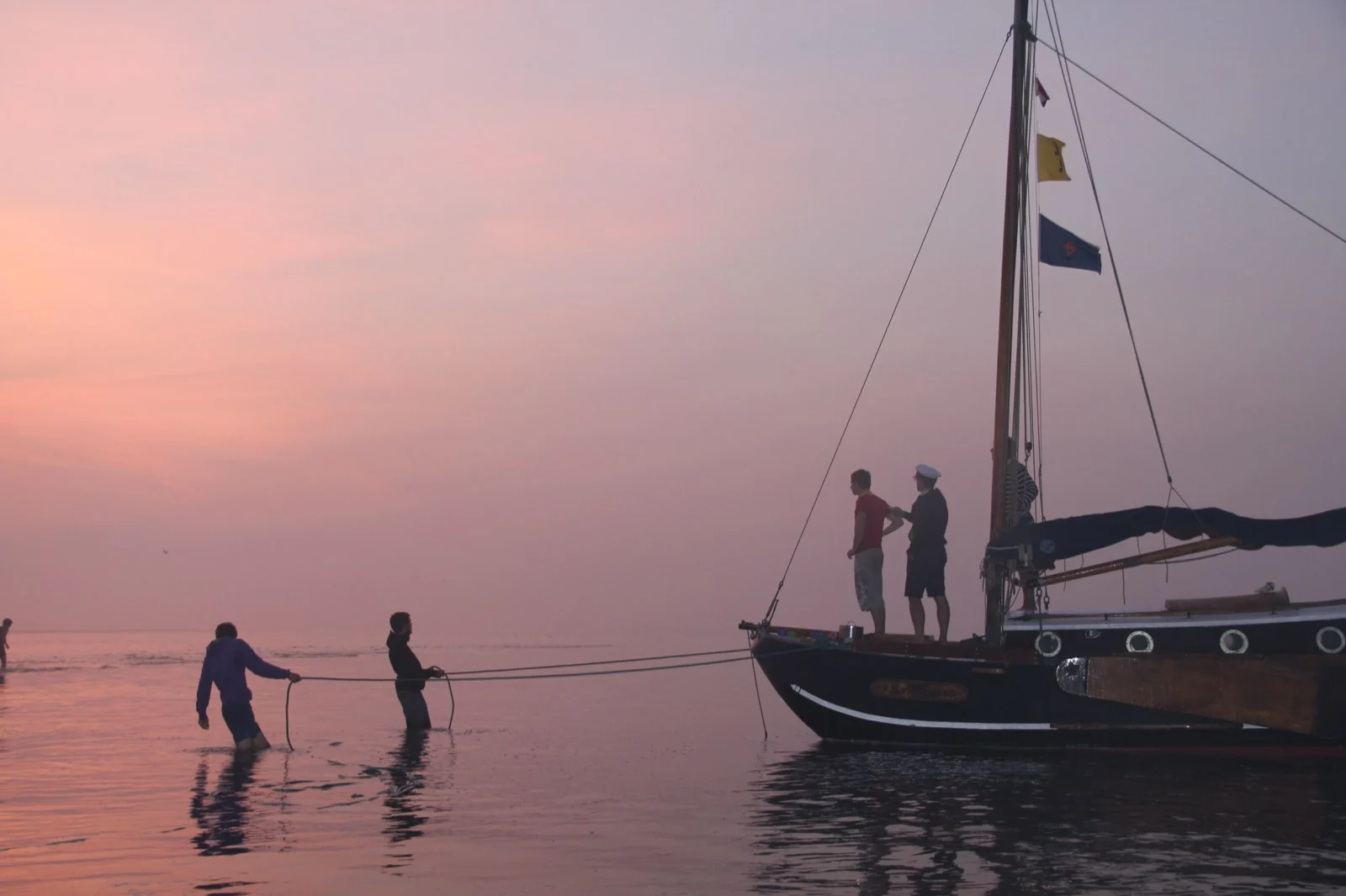 Een zeilboot bij roze valavond op de Schelde