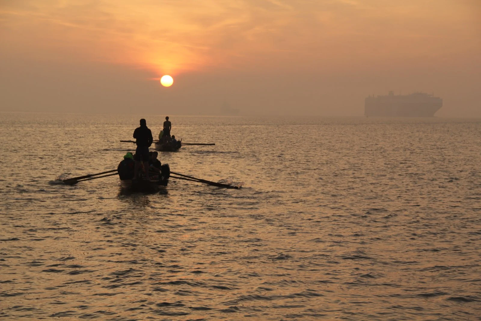 Twee zeescouts roeien bij zonsondergang over de Schelde